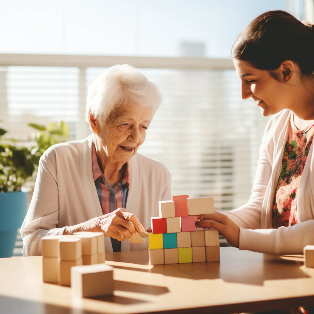 Nurse helping elderly lady with dementia to build blocks